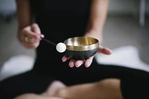 image représentant une femme faisant vibrer un vol chantant dit tibétain pour animer une méditation de groupe. C'est un outil de nettoyage énergétique.